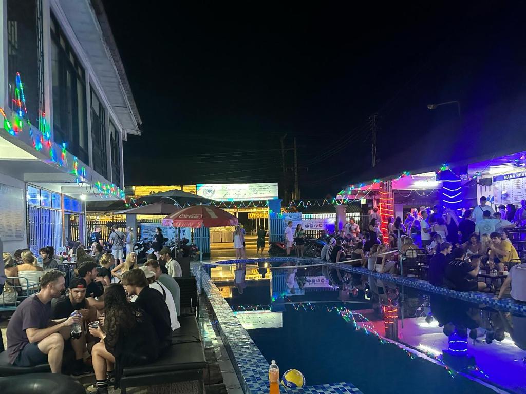 grupa ludzi siedzących w nocy przy basenie w obiekcie Nana Backpackers Hostel w mieście Vang Vieng