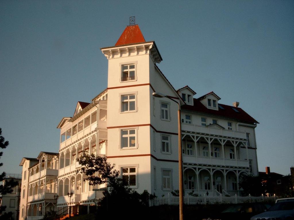 un grand bâtiment blanc avec une tour en haut dans l'établissement Pension Haus Edelweiß, à Binz