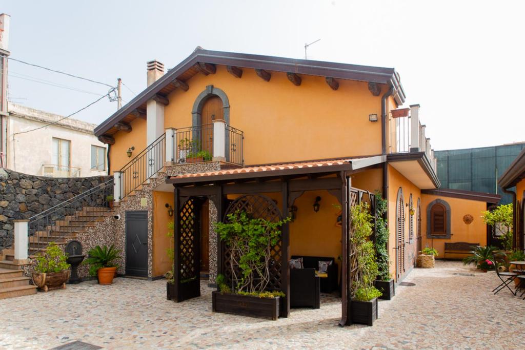 una casa amarilla con plantas en un patio en B&B Villa Liliya en Fiumefreddo di Sicilia