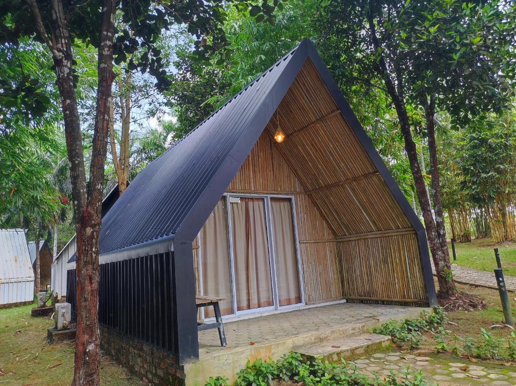 una pequeña casa con techo negro en "D'BAMBOO KAMP" Desa Wisata Ekang en Lagoi