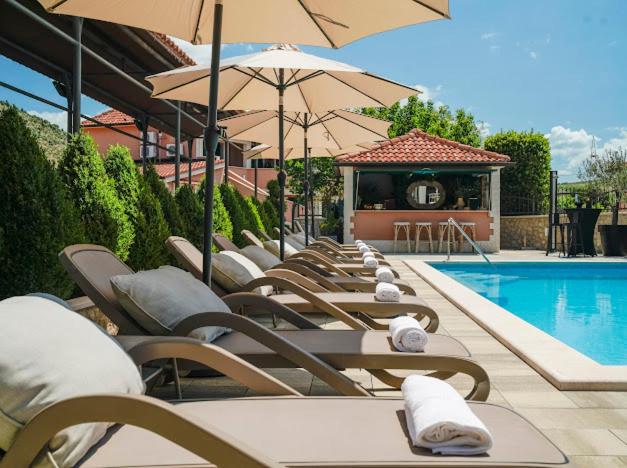 a row of lounge chairs with umbrellas next to a swimming pool at Apartments Antonia in Šibenik