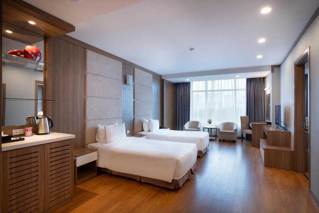 Muong Thanh Grand Hanoi Hotel في هانوي: غرفة فندقية بسريرين ومكتب