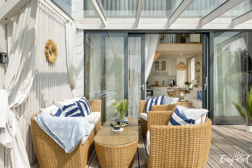 an outdoor patio with wicker chairs and a table at Nowoczesny Domek z Jacuzzi 1 in Wrzosowo