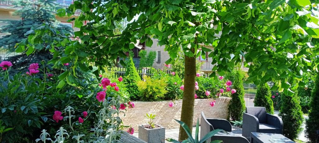 un jardín con flores rosas y un árbol en Pokoje, en Maniowy