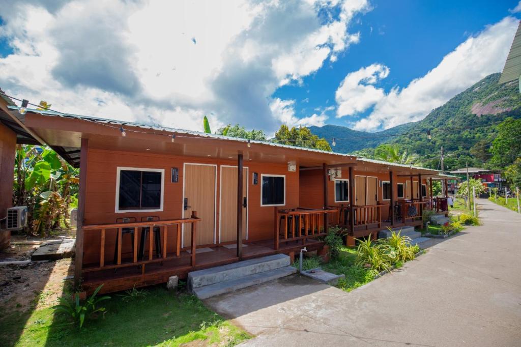 ein kleines Haus mit einer Veranda und Bergen im Hintergrund in der Unterkunft Paya Debloc Village in Tioman Island