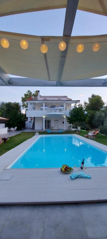 una grande piscina con una casa sullo sfondo di HEAVENLY VIEWS-2- Elegant Ground floor Apartment with pool Close to the Beach!! a Oropos