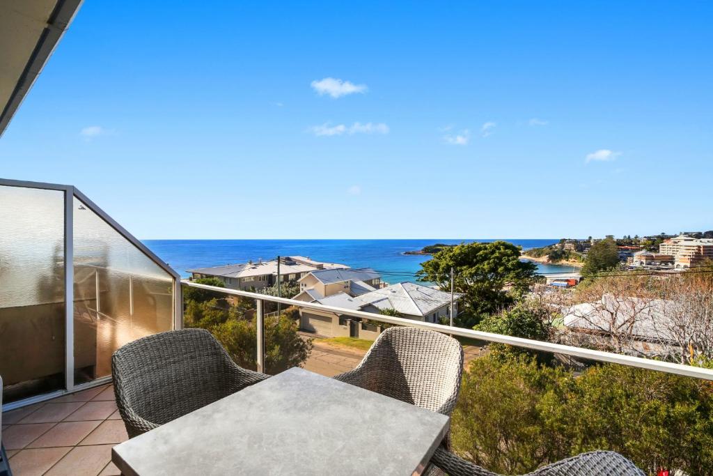 einen Balkon mit einem Tisch, Stühlen und Meerblick in der Unterkunft Scenic Beachside Apartment, near Bar & Restaurant in Terrigal
