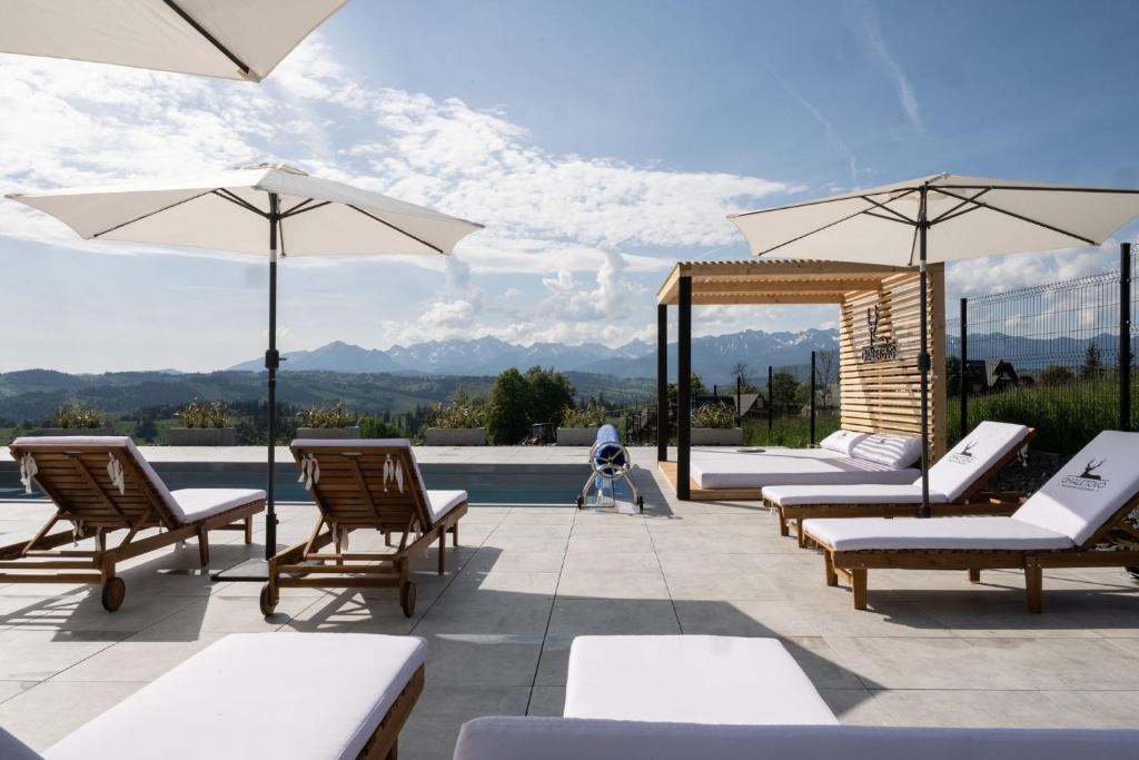 a patio with chairs and umbrellas next to a pool at Chaletovo Mountain Residences in Zakopane
