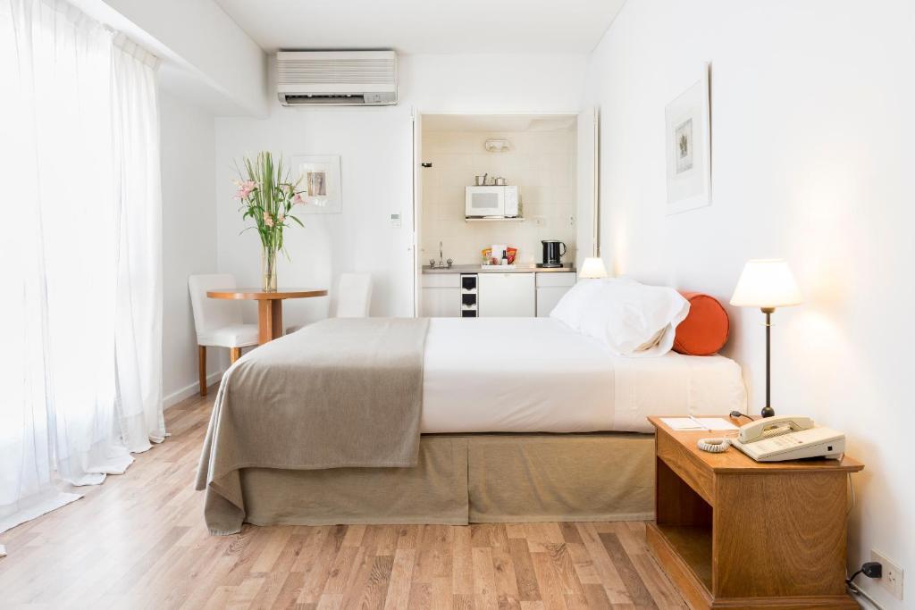 1 dormitorio con 1 cama y 1 mesa con teléfono en Loi Suites Esmeralda en Buenos Aires