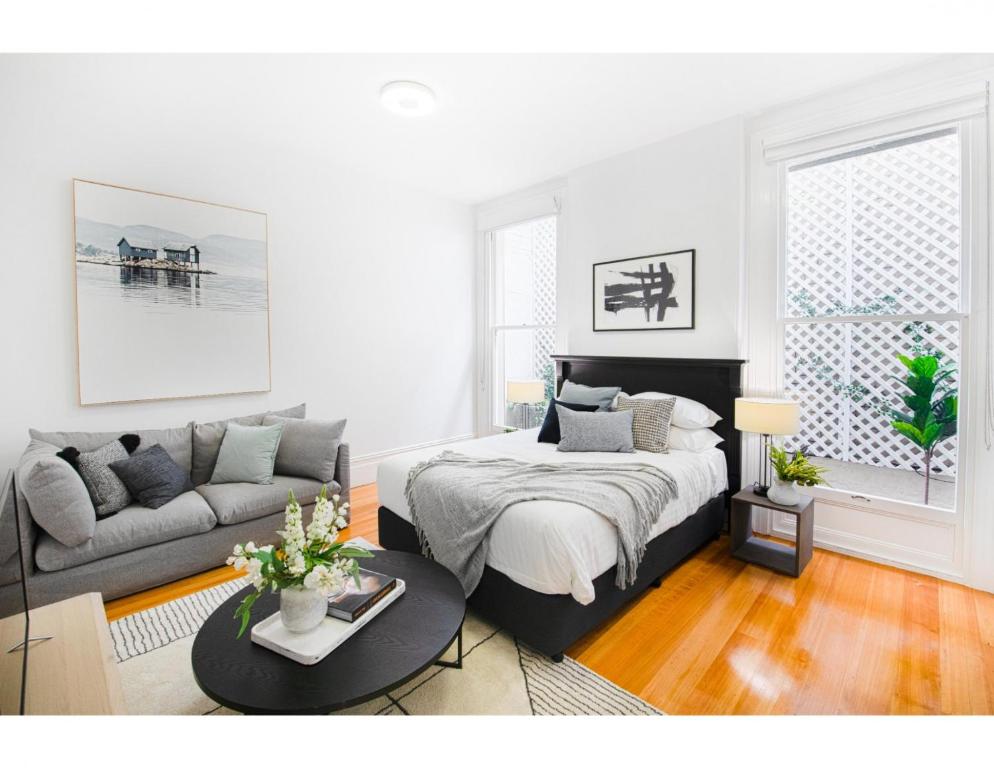a white bedroom with a bed and a couch at Renovated studio in bohemian area close to city in Sydney