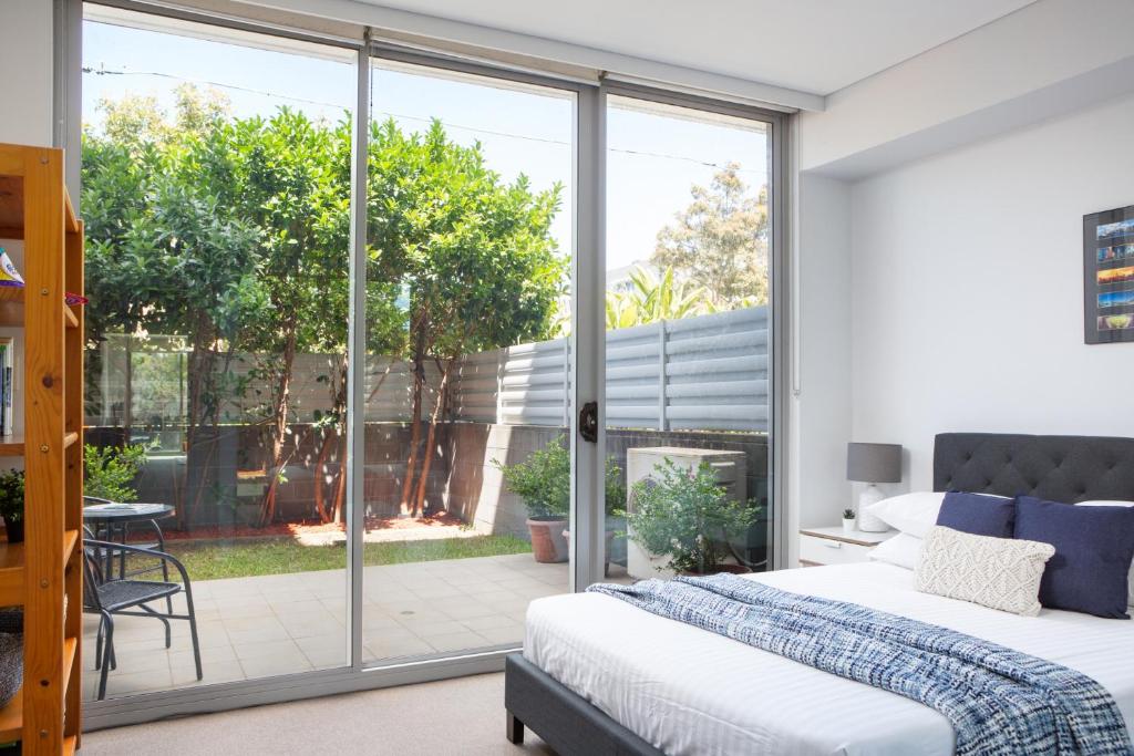 een slaapkamer met een bed en een glazen schuifdeur bij Spacious Modern Apartment In Sydney's North Shore in Sydney