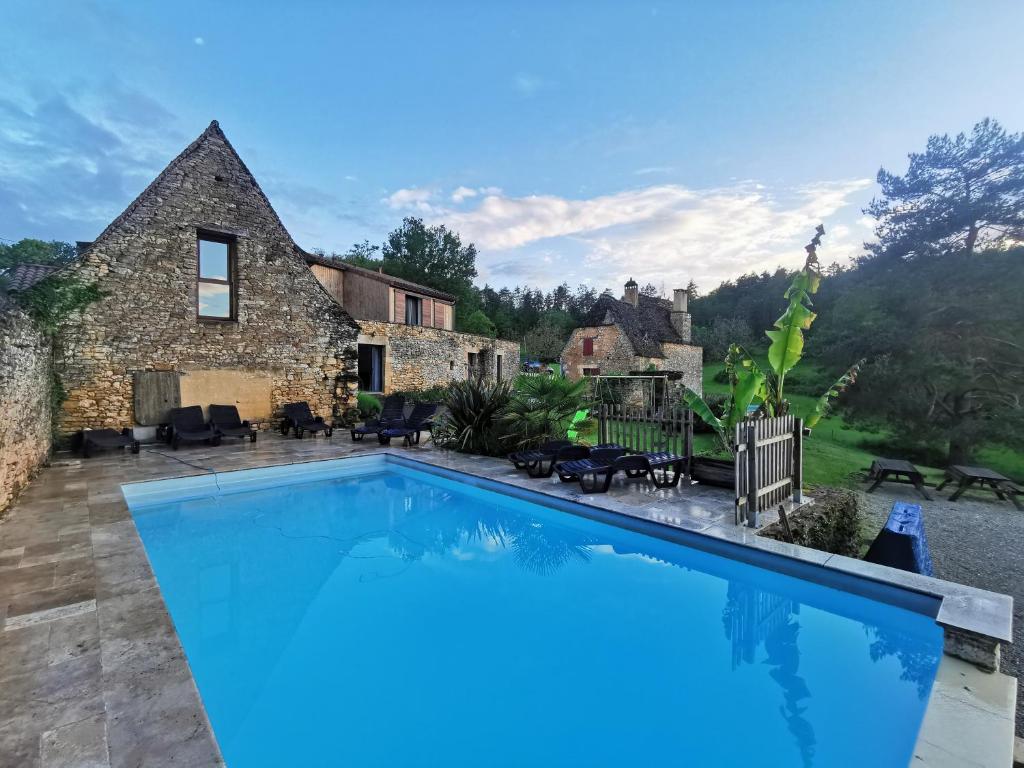 una gran piscina frente a una casa de piedra en Gîte Les Combes Montignac Lascaux en Montignac