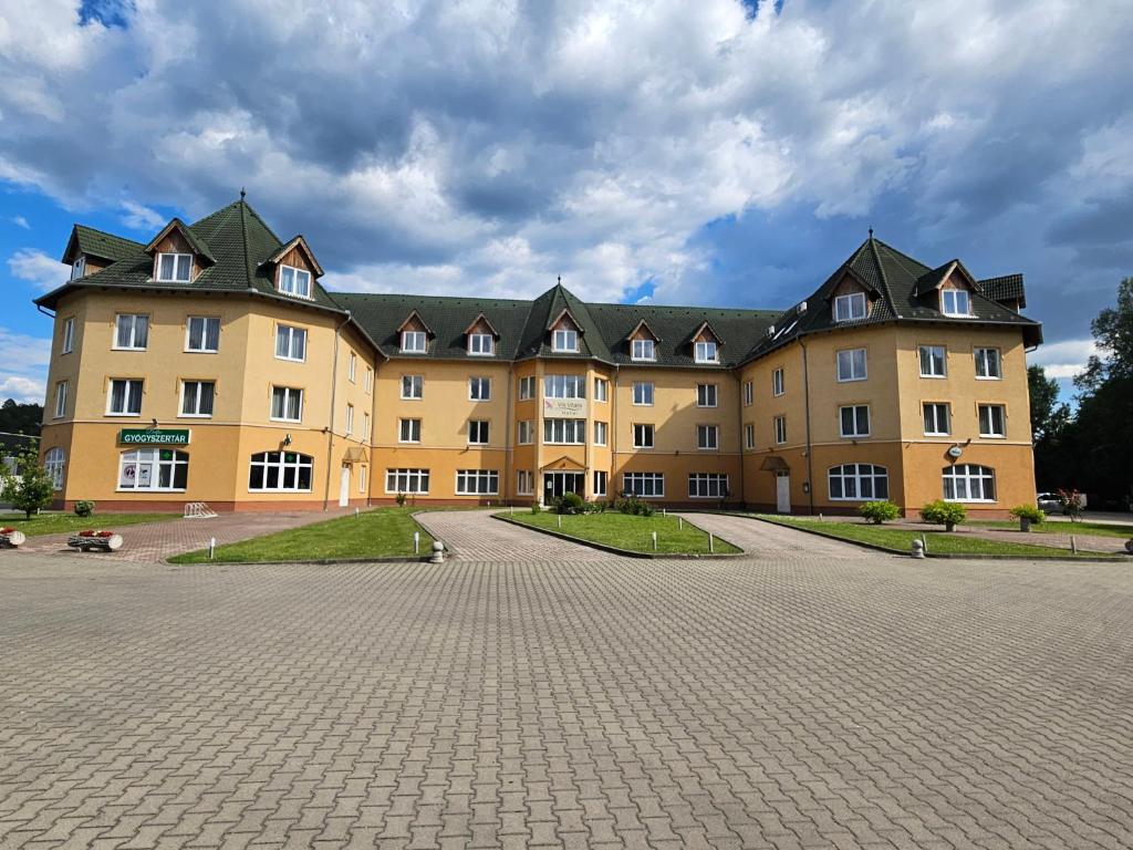 a large yellow building with black roof at Vis Vitalis Hotel in Kerepes