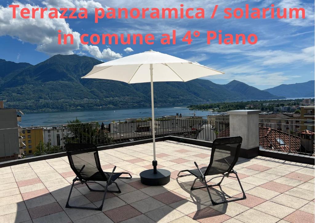 eine Terrasse mit zwei Stühlen und einem Sonnenschirm auf dem Dach in der Unterkunft Tripolitania in Minusio