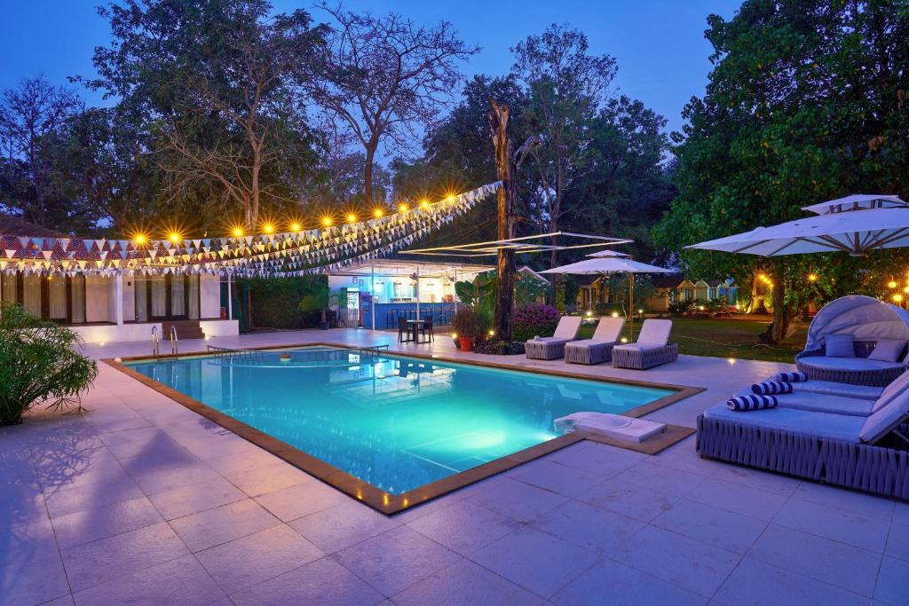 einen Pool mit Beleuchtung und Stühlen sowie eine Terrasse in der Unterkunft Blu Resorts in Vagator