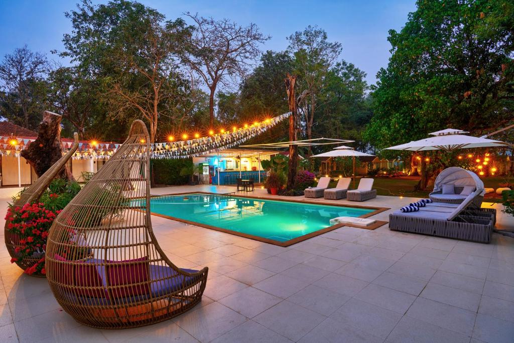 a pool with a hammock and chairs and lights at Blu Resorts in Vagator