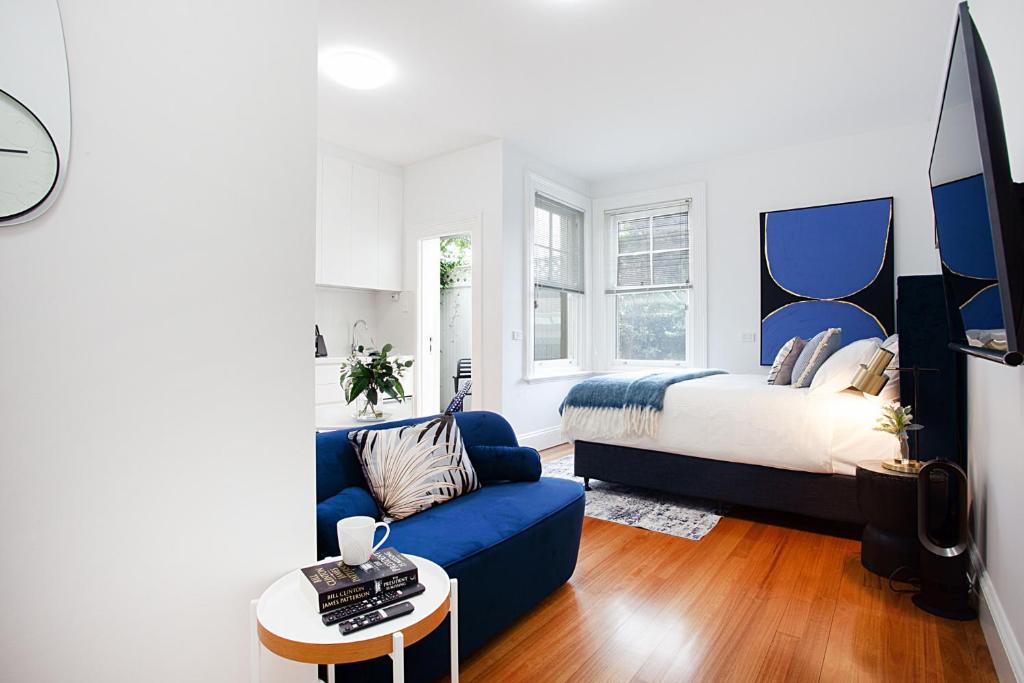 a living room with a bed and a blue couch at Bright and Beautiful Studio in Quiet Neighbourhood in Sydney