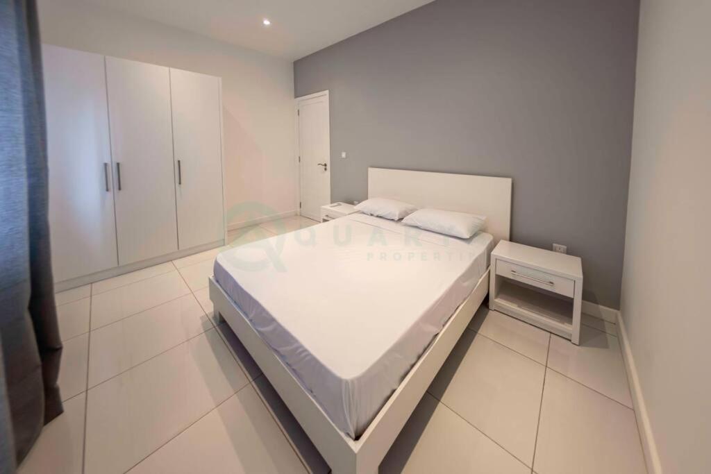 a white bedroom with a large bed and cabinets at Modern Oceanview Apartment D1 in Flic-en-Flac