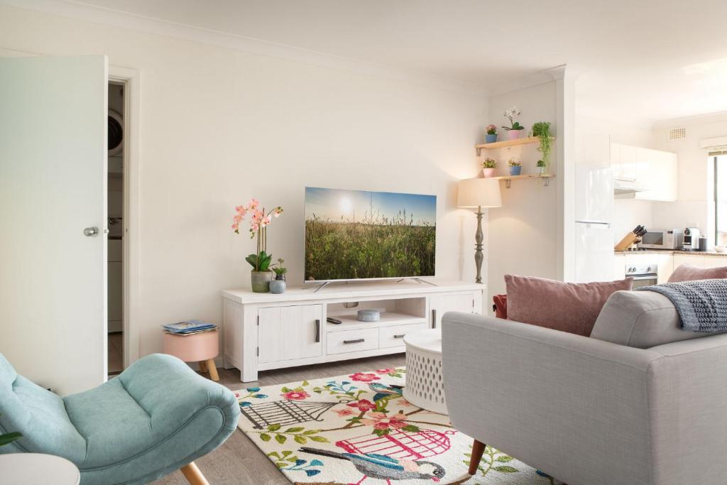 Cosy 2-Bed Apartment in the Heart of Strathfield في سيدني: غرفة معيشة مع تلفزيون على خزانة بيضاء