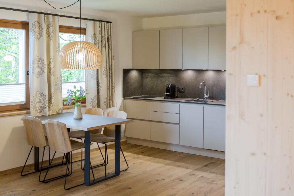 a kitchen with white cabinets and a table and chairs at Haus Widmann in Fieberbrunn