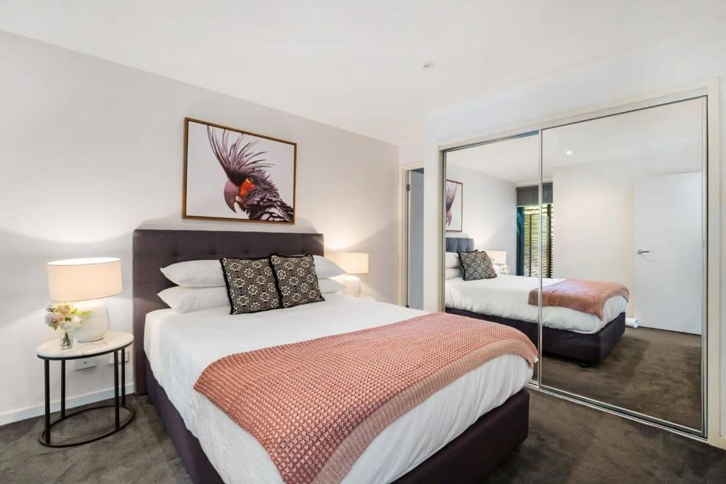 een slaapkamer met 2 bedden en een spiegel bij Chic 2-Bed Oasis in South Melbourne's Heart in Melbourne