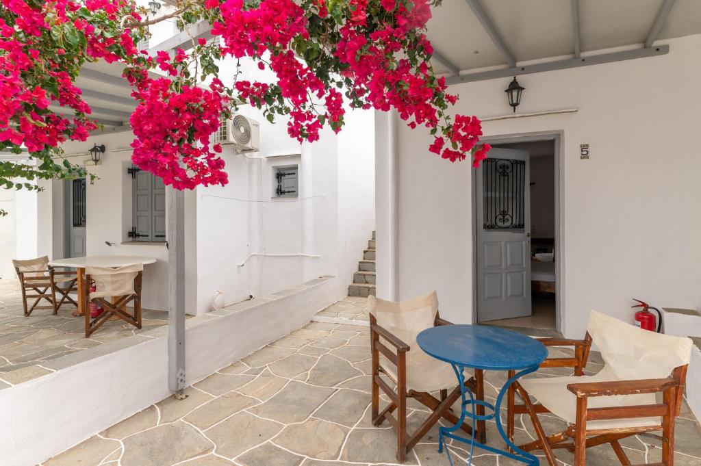 un patio con mesa, sillas y flores rosas en Sifnos studio 5 en Sifnos