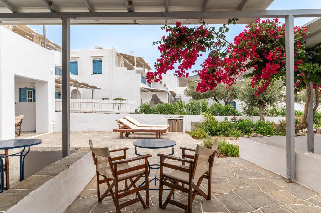 a patio with tables and chairs and pink flowers at Sifnos studio 5 in Sifnos