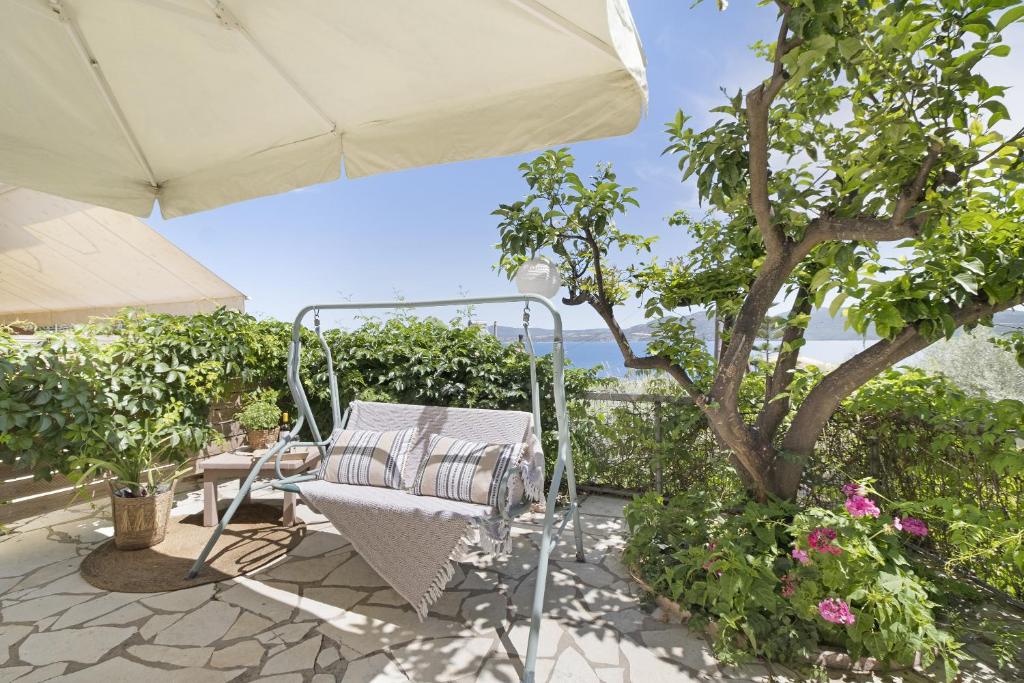 een patio met een stoel en een parasol bij Tasoula Studio with garden view in Nikiana