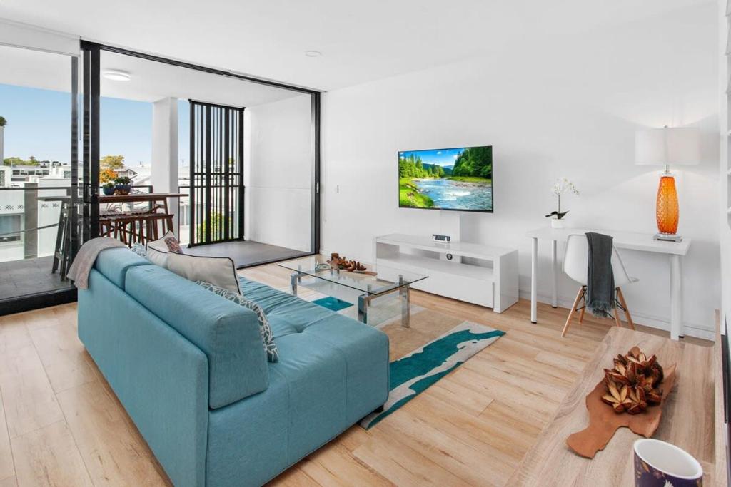 uma sala de estar com um sofá azul e uma televisão em Spacious 2-Bed Unit With Balcony Next to The Gabba em Brisbane