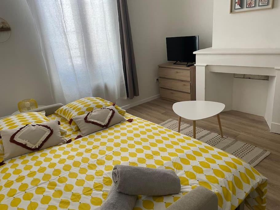 a bedroom with a yellow and white bed and a chair at L'entre Stud' in Castres