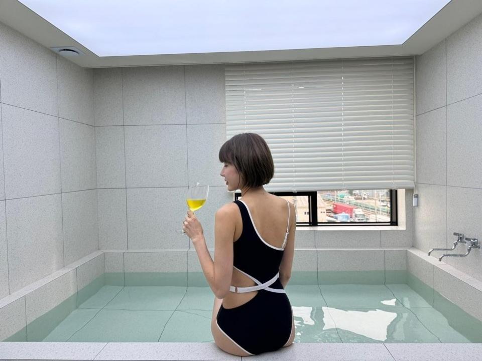 a woman sitting in a bath tub holding a glass of wine at Hound Hotel Gijang Osiria in Busan