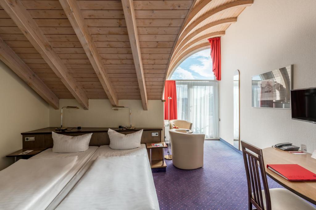 Schlafzimmer mit einem Bett, einem Schreibtisch und einem Fenster in der Unterkunft Andante Hotel Dresden in Dresden
