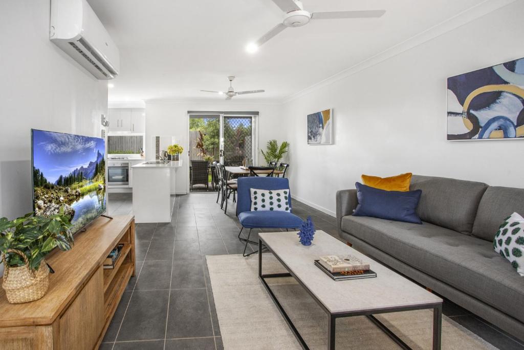 a living room with a couch and a tv at Charming 3-Bed House with Patio near Sport Stadium in Brisbane