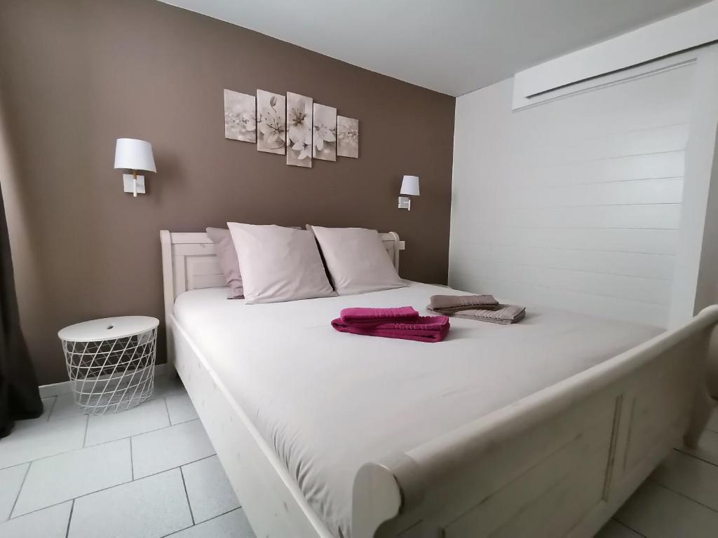 - un lit blanc avec des oreillers blancs et des serviettes roses dans l'établissement Gîte Le Rimbach, à Soultz-Haut-Rhin