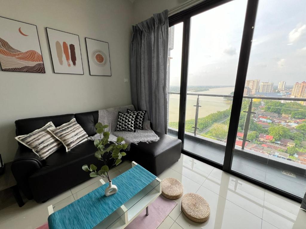 a living room with a black couch and a large window at RiverView 8PAX 3BR in KBtown Wi-Fi, B-12-2 in Kota Bharu