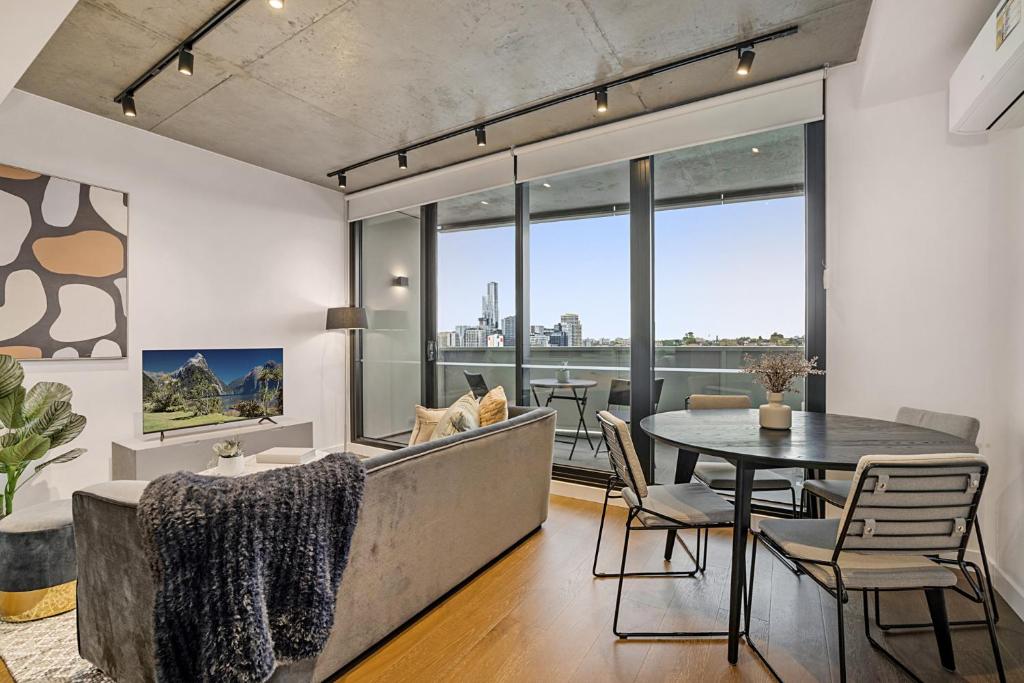 un soggiorno con tavolo, sedie e una grande finestra di Modern, Executive 1 Bedroom Apartment With Balcony a Melbourne