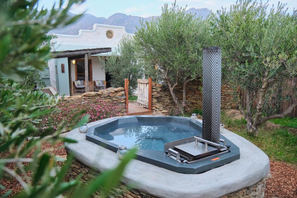 a hot tub in a yard in front of a house at Olive Stone Farm Cottages in Montagu