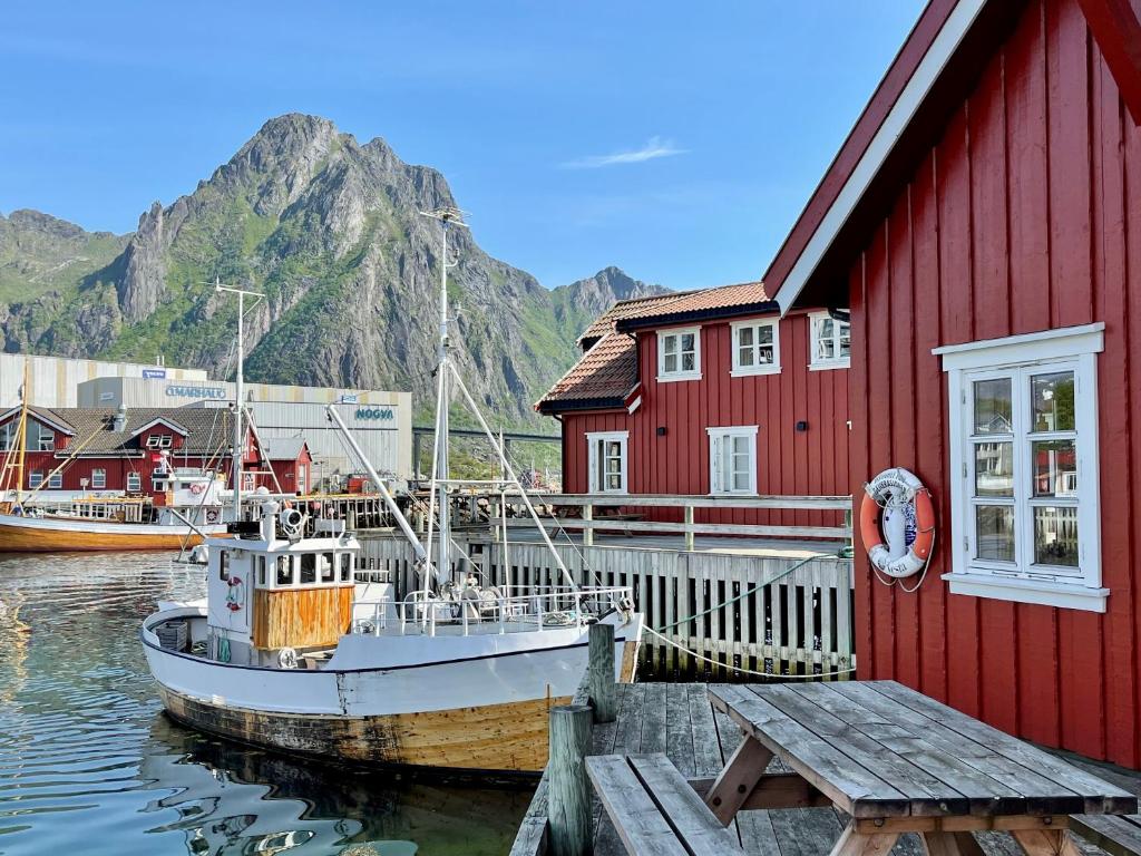 a boat is docked next to a red building at Anker Brygge in Svolvær