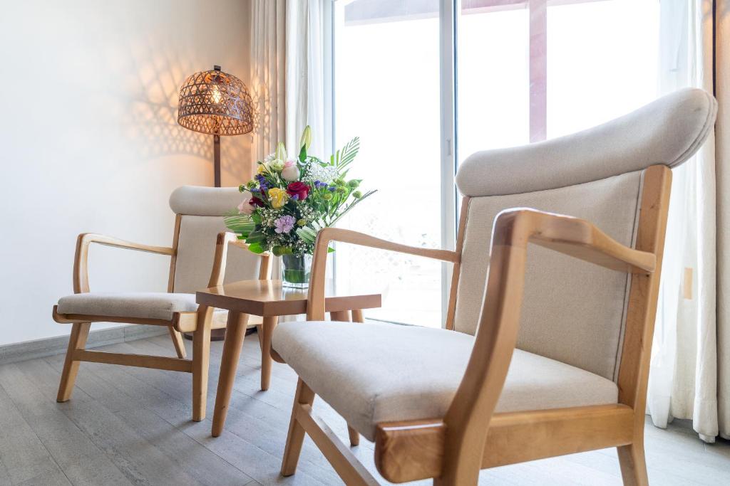 a room with two chairs and a table with a vase of flowers at Beach Walk Boutique Jumeirah in Dubai