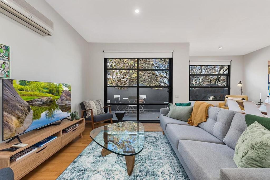 a living room with a couch and a large tv at Beautiful 2-Storey Unit with Balcony near Smith St in Melbourne
