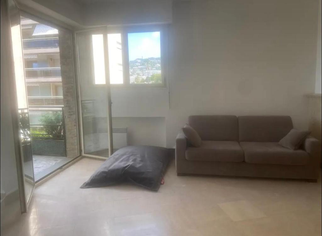 Una sala de estar con un sofá y algunas ventanas. en palm Beach studio vue port Canto, en Cannes