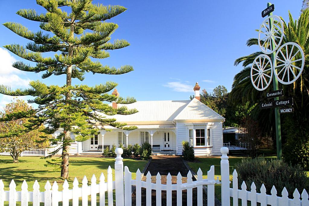 a white picket fence in front of a white house at Coromandel Cottages in Coromandel Town