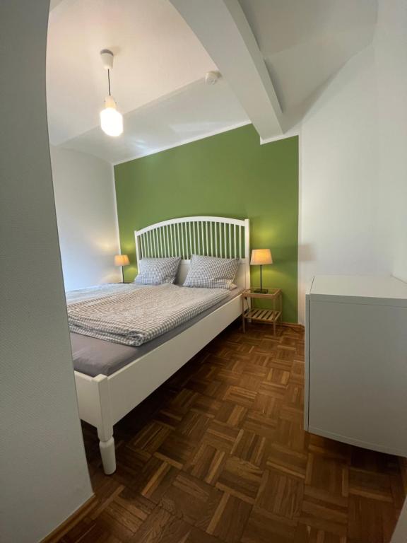 a bedroom with a bed with green walls and wooden floors at Landurlaub auf Hinners-Hoff in Bendingbostel