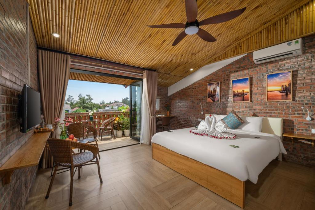 1 dormitorio con 1 cama y ventilador de techo en Hoi An Golden Bamboo An Bang Beach Villa & Spa, en Hoi An
