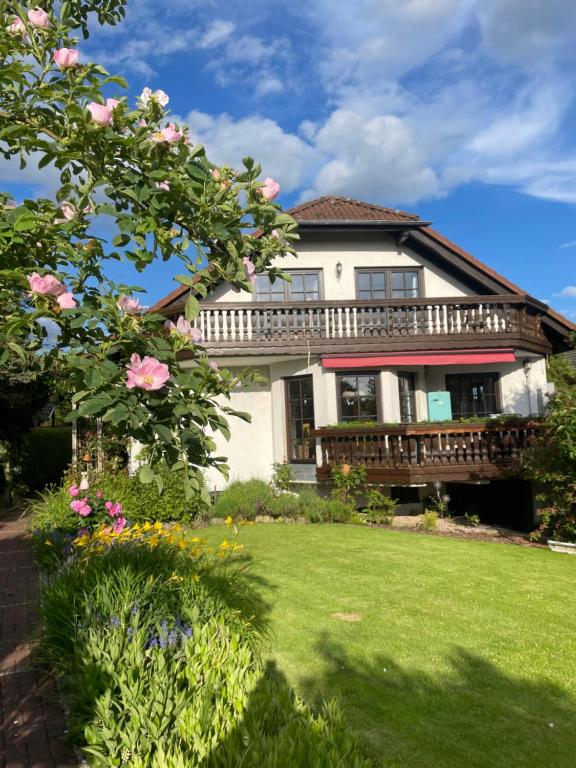 ein Haus mit einem Balkon und einem Garten mit Blumen in der Unterkunft Ferienwohnung AUSZEIT in Immenhausen