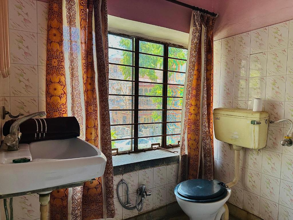 a bathroom with a toilet and a sink and a window at JWALA JAIPUR in Jaipur