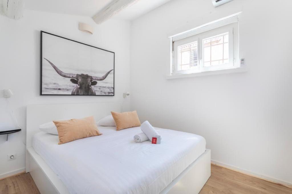 une chambre avec un lit blanc avec une photo de taureau sur le mur dans l'établissement Cosy apartment Vieux Port- 27ORV, à Marseille