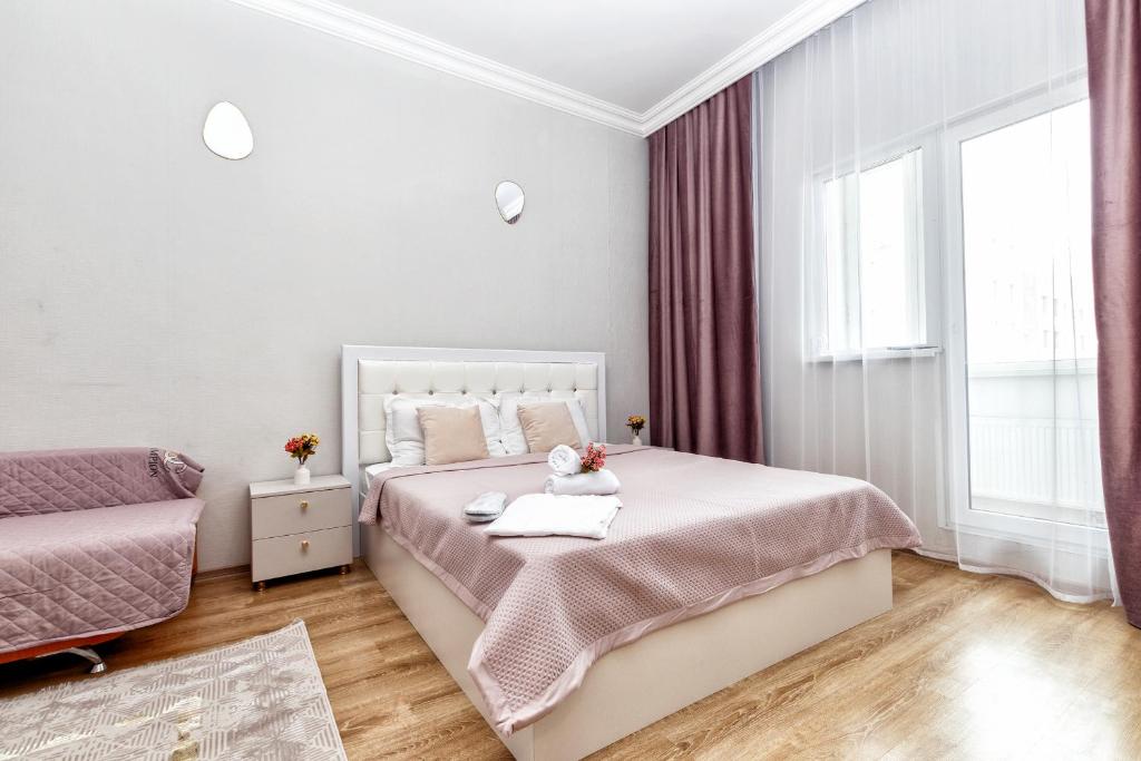 a white bedroom with a bed and a window at Красивые апартаменты на Экспо in Taldykolʼ