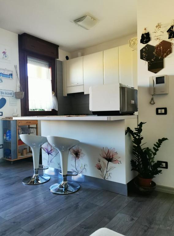 a kitchen with two white stools in a room at SunDays House #casa al mare in Quartu SantʼElena