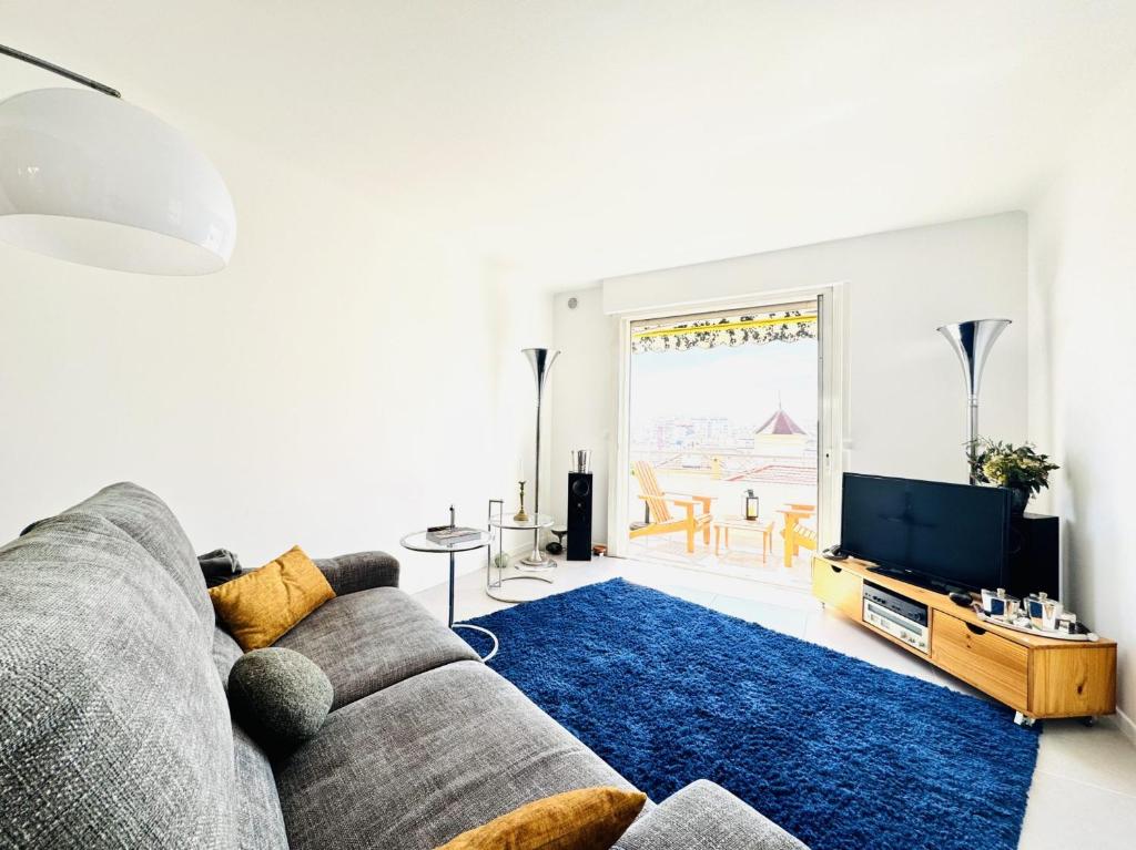 un salon avec un canapé et une télévision dans l'établissement L'impérator - Petit Juas Cannes, à Cannes